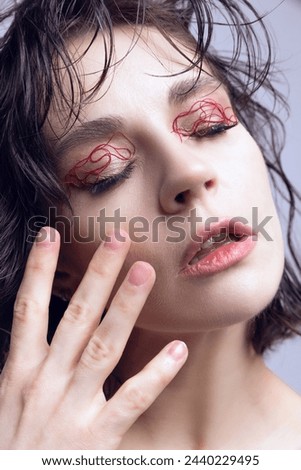 Close-up portrait of young beautiful girl with wet hair, red string makeup on eyelids. Revolutionary skincare treatment. Concept of modern beauty standards, plastic surgery, health, cosmetology