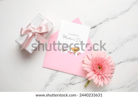 Envelope with festive postcard, gift box and flower on white grunge background. Happy Mother's Day