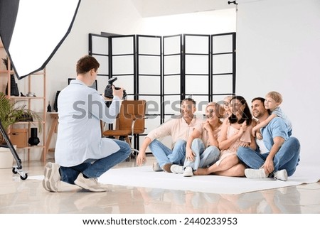Male photographer taking picture of big happy family in studio