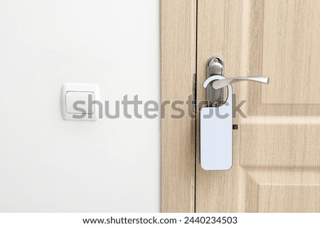 Light wooden door in hotel room with door hanger