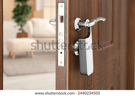 Opened dark wooden door with door hanger in hotel room