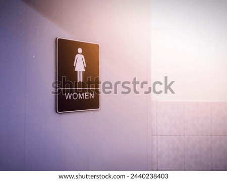 A sign with a woman and letters attached to the light-filled bathroom door.