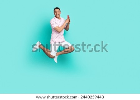 Full size photo of positive guy dressed t-shirt white shorts running to empty space hold smartphone isolated on teal color background