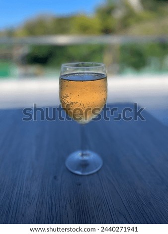Exterior visual photo view of a fresh glass of sparkling alcohol on a wood table at a terrace in a restaurant with nice weather to drink drinking thirsty champagne wine  by sunny weather