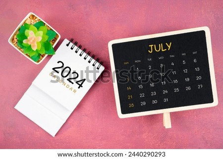 Calendar for July 2024 in black chalkboard on red wooden background.