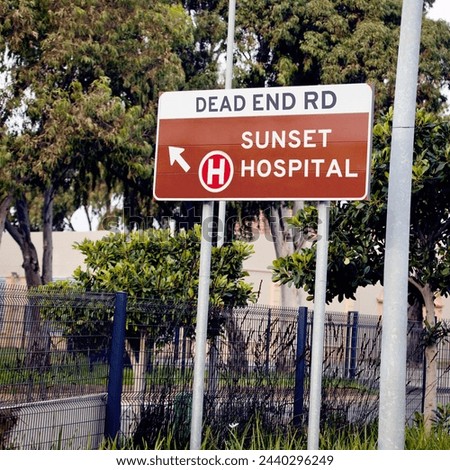 City, outdoor and information with road, signage and text with icon for hospital and symbol with nature and urban town. Street, direction to a medical facility and outdoor with fence, board and tree