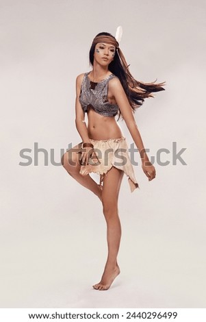 Performance, dancing and Native American woman in studio with warrior makeup, confidence and tribe style. Indigenous fashion, face paint and proud girl in First Nations clothes on white background