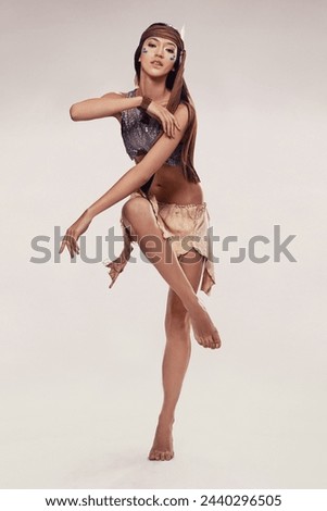 Portrait, woman and Native American dance in studio with warrior makeup, confidence and tribe style. Indigenous fashion, performance and girl in First Nations clothes on white background with culture