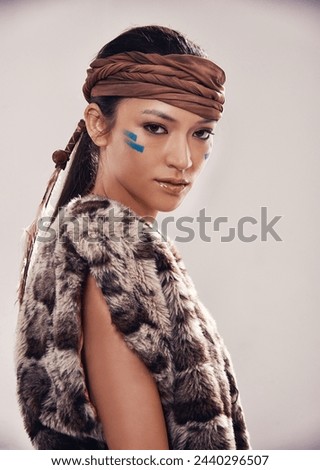 Portrait, girl and Native American culture in studio with warrior makeup, confidence and tribe style. Indigenous fashion, face paint and serious woman in First Nations clothes on white background