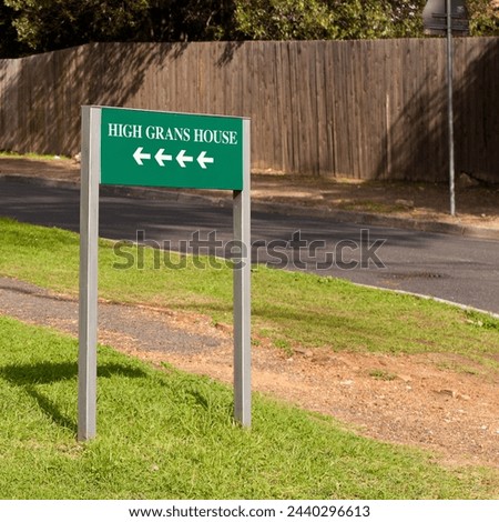 Road sign, arrow and outdoor for direction in neighborhood to search for houses, address and funny joke. Green board, signage and pointing on grass, lawn and comic text with mistake, error or humor