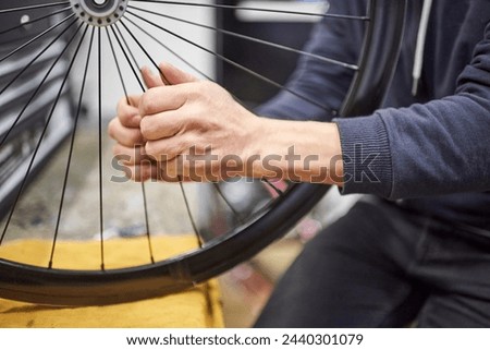 Unrecognizable man checking the tension of the spokes of a bicycle wheel in his bike workshop. Real people at work.