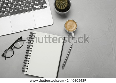 Flat lay composition with open notebook and laptop on light grey table