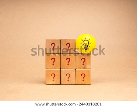 Creative idea and innovation, unique, difference, leadership, solutions and motivation concepts. Smart light bulb on yellow ball on wooden cube block stack with question symbol on brown background.