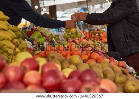 Closeup of hands of seller and customer handing over fruit and money at a stall at the Barcelos fair