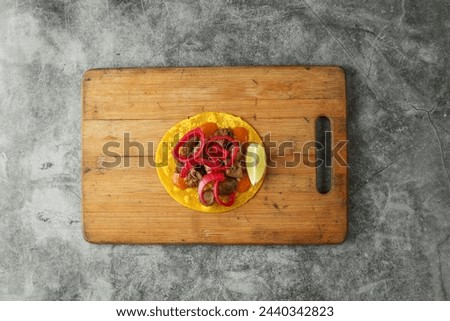Beef and tomato tacos on wooden board, placed on marble grey background, studio shot