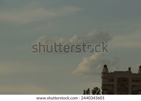 Building against blue sky with white cumulus clouds Royalty-Free Stock Photo #2440343601