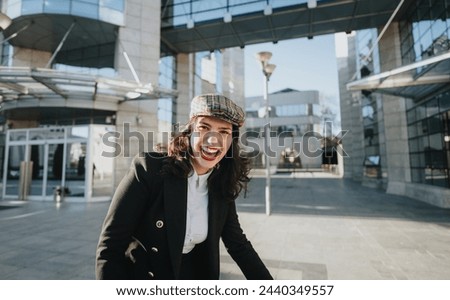 Cheerful young woman with a trendy look enjoys a break outside modern office buildings, reflecting urban work-life balance.