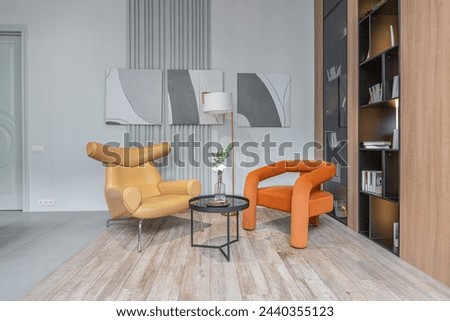 sitting area with two soft stylish armchairs in huge modern spacious apartment with high loft style ceilings, wooden decoration and grey walls