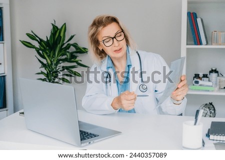 Female doctor makes online video call consult patient on laptop. Middle aged woman therapist videoconferencing for domestic health treatment. Telemedicine concept. Online remote medical appointment. Royalty-Free Stock Photo #2440357089