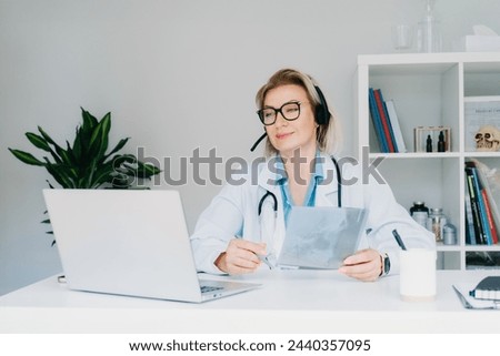 Female doctor in headset make online video call consult patient on laptop. Middle aged woman therapist videoconferencing for domestic health treatment. Telemedicine. Online remote medical appointment. Royalty-Free Stock Photo #2440357095