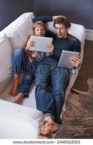 Father, son and tablet for gaming on sofa together, technology and online streaming for bonding at home. Digital world, internet and man with boy child in living room, gamer app and entertainment