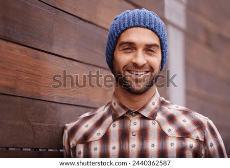 Portrait, smile and man on wood wall background outdoor in casual clothes, outfit or apparel. Face, happy and stylish person in beanie, shirt and trendy fashion for profile picture with hat in Spain