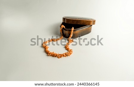 In the foreground, a pink coral necklace emerges from a small wooden box of old-fashioned blurred on a white background. bokeh. copy space. Royalty-Free Stock Photo #2440366145