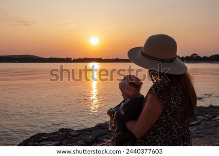 Loving mother holding small toddler enjoying romantic sunset in Medulin, Istria, Croatia, Europe. Coastline of Kvarner Gulf in Adriatic Mediterranean Sea. Dreamlike atmosphere. Family vacation concept Royalty-Free Stock Photo #2440377603