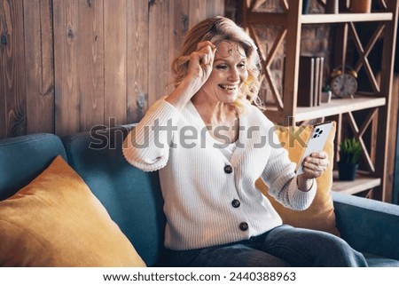 Photo portrait of lovely retired woman sofa read good news device dressed casual outfit cozy home interior living room in brown warm color