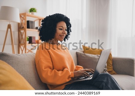 Photo portrait of lovely young lady working remotely netbook dressed casual orange clothes cozy day light home interior living room