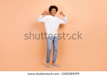 Photo of cheerful satisfied man dressed white denim outfit thumb up nice quality good job isolated on beige color background