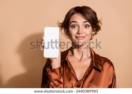 Photo of positive funky lady dressed brown shirt showing modern device empty space isolated beige color background