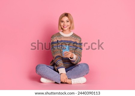 Full size photo of good mood intelligent woman wear ornament pullover sit with smartphone in hand isolated on pink color background