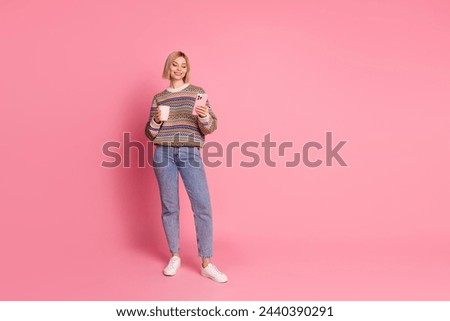 Full size photo of good mood woman wear ornament pullover hold cup of latte read email on smartphone isolated on pink color background