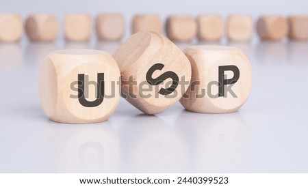 three wooden cubes with the letters USP on the bright surface of a gray table. the inscription on the cubes is reflected from the surface of the table. USP - short for Unique Selling Proposition