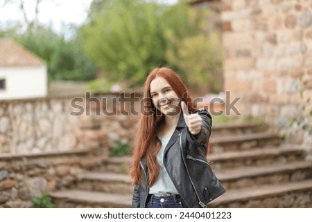 Young woman with long hair extends her hand and raises her thumb giving her approval Royalty-Free Stock Photo #2440401223