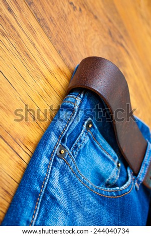 Aged blue jeans with a leather belt on wooden boards. copy space