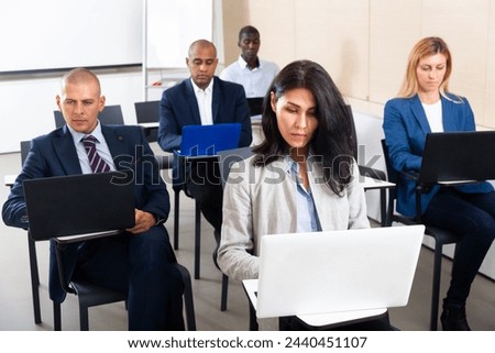 Portrait of concentrated businesspeople working on laptops during corporate seminar in office meeting room