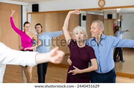 Happy older couple performing a paired ballroom dance in ballroom