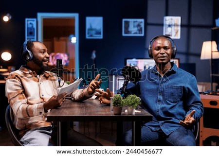 Live talk show is hosted by a dynamic duo discussing various topics and interacting with fans. Black men using professional microphones to produce high quality content for online streaming service.