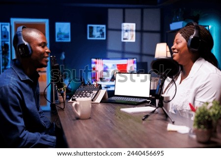 Cheerful couple are conversing while the laptop displays a blank copyspace mockup template. A portable computer displays an isolated white screen template that advertises an online streaming platform.
