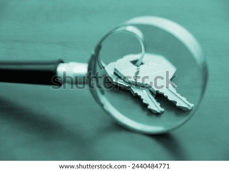 Real estate review concept. Keys under magnifying glass on table.
