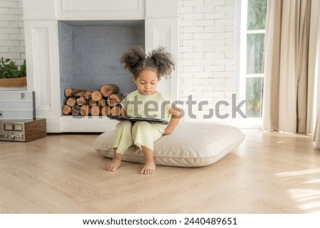 African American little girl playing and using a tablet at home