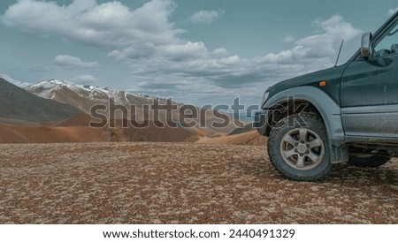 An off-road car on the background of mountains. A tourist car with off-road tires. A car with a mountain view. Transport for travel.