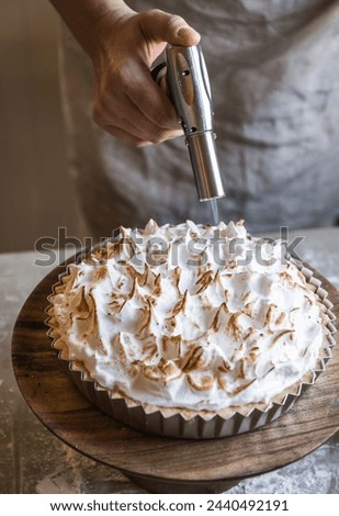 Chef using gas burner on lemon meringue pie