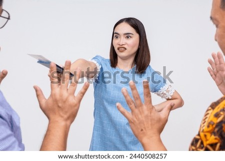 An angry female traveler is shown exchanging heated words with airport officials, holding her passport and boarding pass visibly. Royalty-Free Stock Photo #2440508257