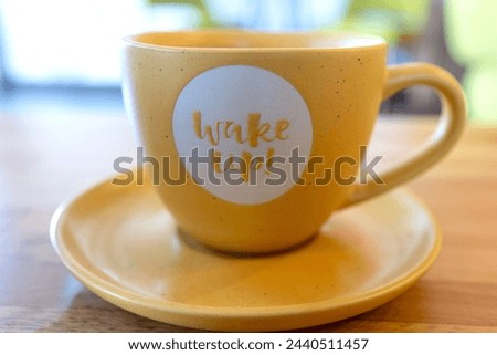 Wake up, message of the brand new day. Sign letters. Close up detail of coffee cup. Blurry background.