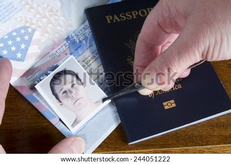 Hand with tweezers holding id photo over passport as if forging the travel documents Royalty-Free Stock Photo #244051222