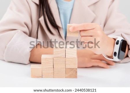 little business girlplacing wooden blocks to represent the peak of the boom to grow their business goals, financial statistics.