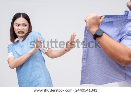 Shocked Asian woman gestures to stop as man commits an act of indecent exposure, both isolated on a white background. Royalty-Free Stock Photo #2440541341